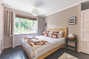 Une chambre à coucher avec un lit, une fenêtre, une table de chevet et une porte.