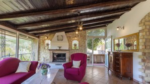 A cozy living room with a fireplace, red armchairs, and a stone wall. - Villa Falcone (Piazza Armerina)