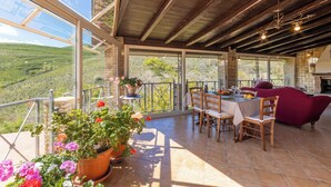 A spacious balcony with a table set for dining, potted plants, and a view of the countryside. - Villa Falcone (Piazza Armerina)