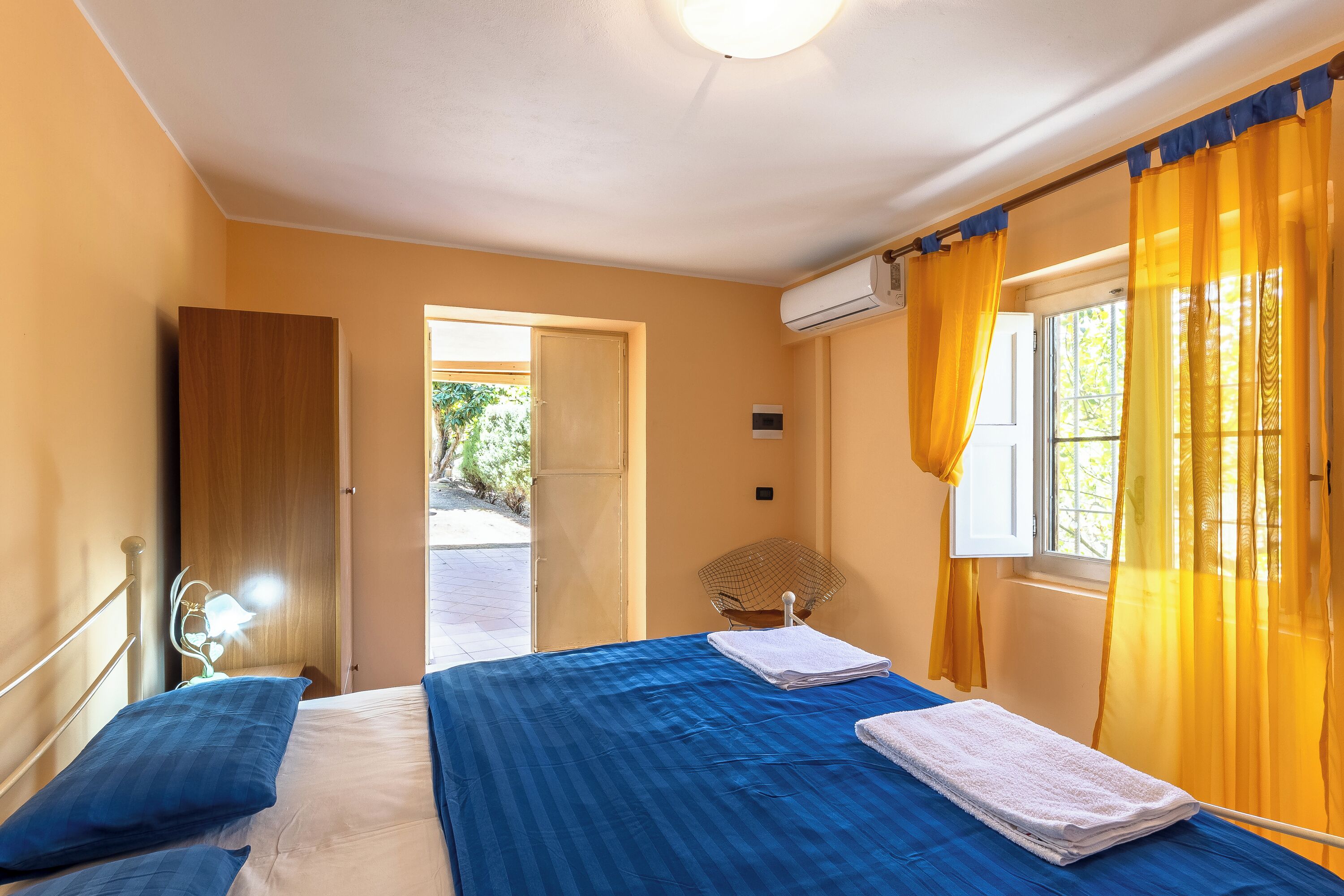 Une chambre à coucher avec un lit, une chaise et une fenêtre avec des rideaux.