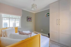 A bedroom with a bed, a window, a wardrobe, and a ceiling light fixture.
