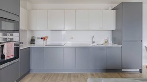 A modern kitchen with grey cabinets, a white countertop, and a Bosch oven.
