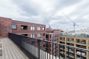 Un immeuble à plusieurs étages, doté d’une façade en briques, de balcons et d’une terrasse en bois.