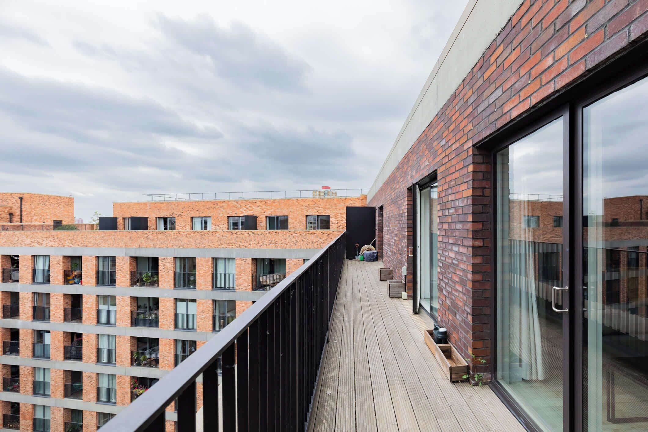 Un edificio moderno con facciata in mattoni, ampie finestre e un terrazza in legno.