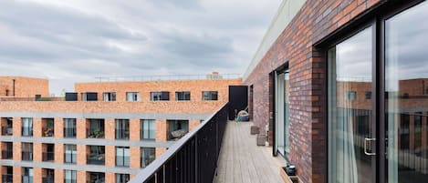 A modern building with a brick facade, large windows, and a wooden deck.