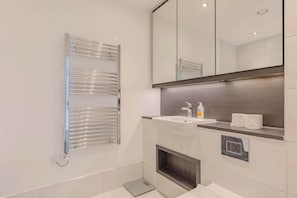 A modern bathroom with a built-in sink, a towel rack, a mirror, and a shower area.