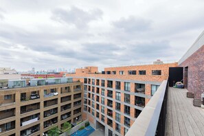 Edifício com vários andares, varandas, um jardim no terraço e um pátio com piscina.