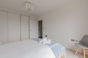 Um quarto com uma cama, uma cadeira e um guarda-roupa.