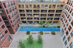 A multi-story building with a central courtyard featuring a swimming pool, surrounded by balconies and greenery.