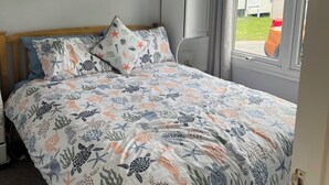 Une chambre à coucher avec un lit, des armoires blanches, une fenêtre et une vue sur l’extérieur.