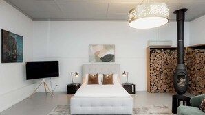 A modern bedroom with a large bed, a flat-screen TV, a fireplace, and artwork on the walls. - Entrepot de Ville (Hobart)
