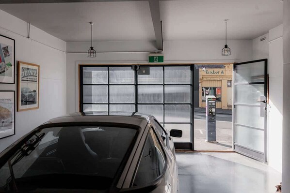 A car parked inside a garage with a large glass door leading to a street.