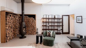 A modern living room with a wood-burning stove, a bookshelf, and a comfortable seating area. - Entrepot de Ville (Hobart)