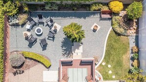 An aerial view of a rooftop garden with seating areas, a central circular seating arrangement, and surrounding greenery. - Carlsbad Cottage - Remodeled (Carlsbad)