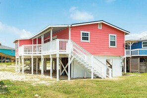 A two-story beach house with a balcony and a staircase leading to the upper level. - The Mermaid Cove Beach House with Ocean Views (Freeport)