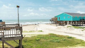 A beach house with a wooden deck and a pier extending into the ocean. - The Mermaid Cove Beach House with Ocean Views (Freeport)