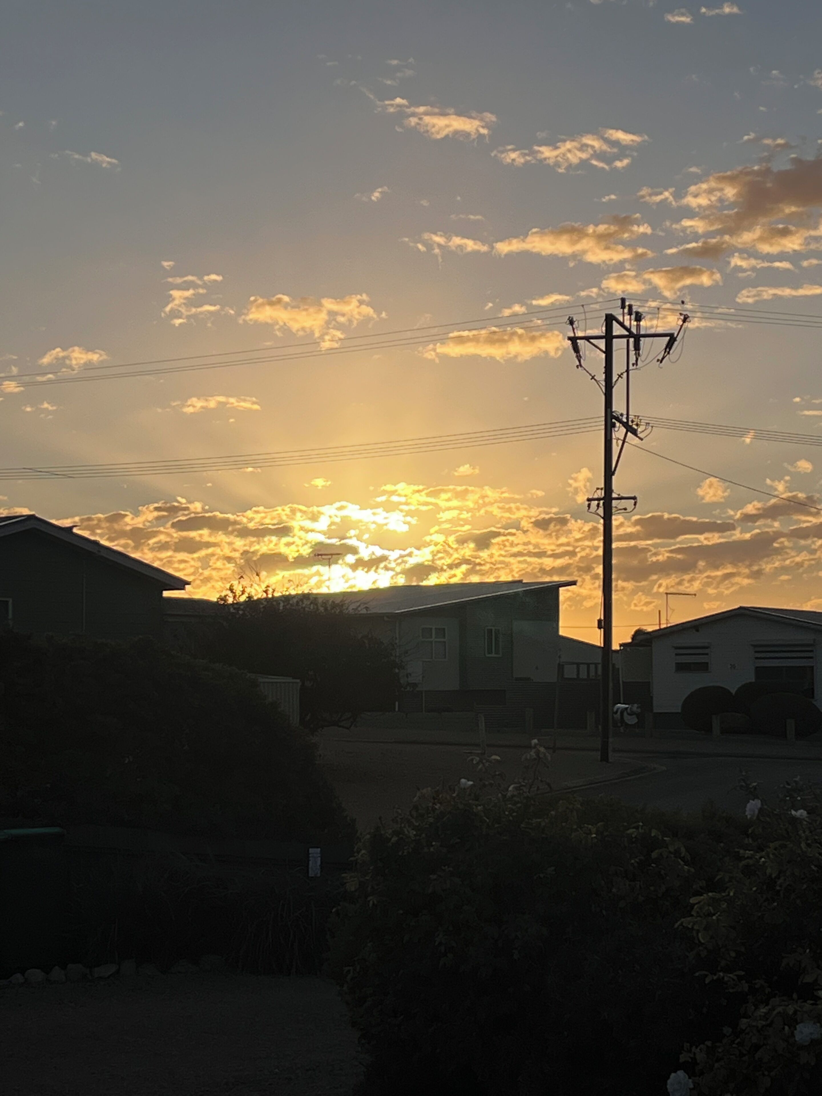 Atardecer sobre un barrio residencial con casas y un poste de luz.