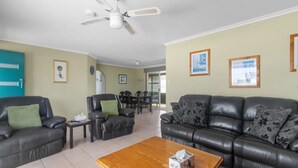 Un salon comprenant un canapé, des fauteuils, une table basse et un ventilateur de plafond.