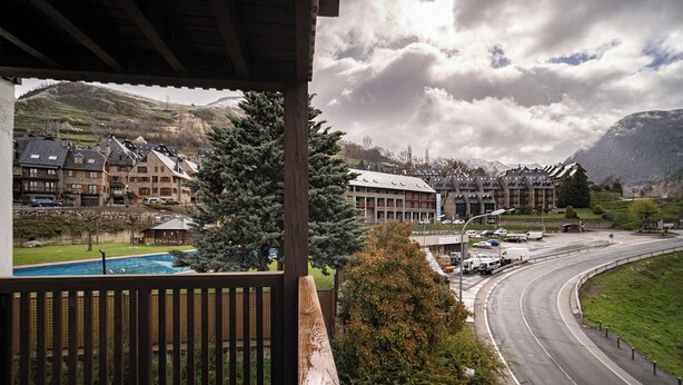 A view of a hotel with a pool, a road, and mountains in the background. - Aran Hostel (Naut Aran)
