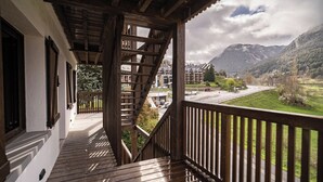A wooden balcony with a view of a road and mountains. - Aran Hostel (Naut Aran)
