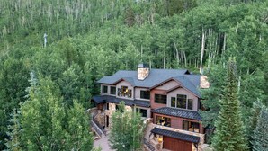 A large, two-story house surrounded by dense forest. - Vail Chalet | Platinum-Rated 4BR Luxury Home, Cascade (Vail)