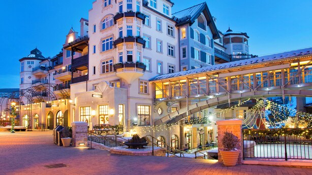 A large, multi-story hotel with a prominent entrance, a covered walkway, and a snow-covered roof.