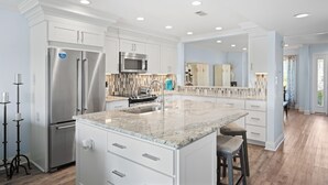 A modern kitchen with white cabinetry, stainless steel appliances, and a granite countertop.