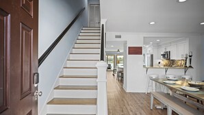 A staircase with white balusters and wooden steps leading to a dining area with a wooden table and chairs.