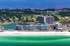 A coastal hotel complex with multiple high-rise buildings, a beachfront, and surrounding greenery.