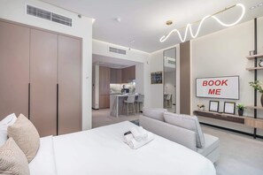 Une chambre d’hôtel moderne équipée d’un lit, d’un canapé, d’un bureau et d’un coin cuisine.
