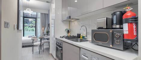 A modern kitchen with a built-in oven, microwave, and coffee maker. There is a fire extinguisher on the counter and a washing machine in the corner.