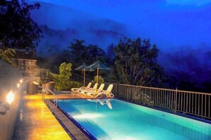 Una piscina al aire libre, sombrillas, tumbonas