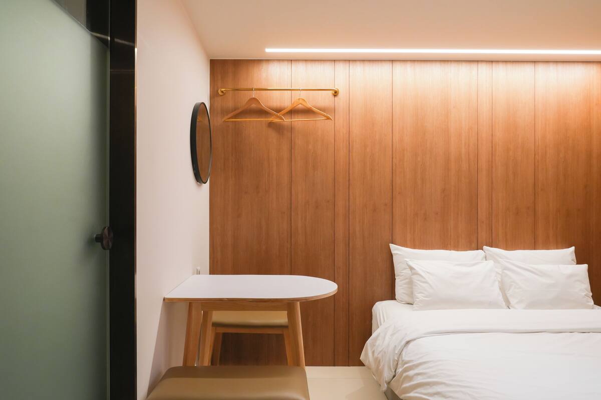 A bedroom with a bed, bedside table, and a wooden wardrobe.