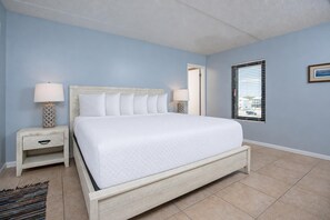 A bedroom with a bed, nightstands, a window, and a door. - Island Winds East 211 3 Bedroom Condo (Gulf Shores)