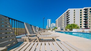 A poolside area with sun loungers and a swimming pool, surrounded by high-rise buildings. - Island Winds East 301 3 Bedroom Condo (Gulf Shores)