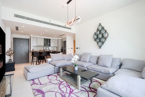 Ein modernes Wohnzimmer mit einem grauen Ecksofa, einem Couchtisch und einem gemusterten Teppich.