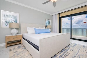 A bedroom with a bed, nightstands, and artwork. There is a balcony with a view.