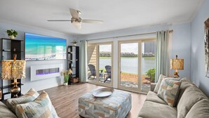 A spacious living room with a large TV, comfortable seating, a fireplace, and a view of the outdoors.