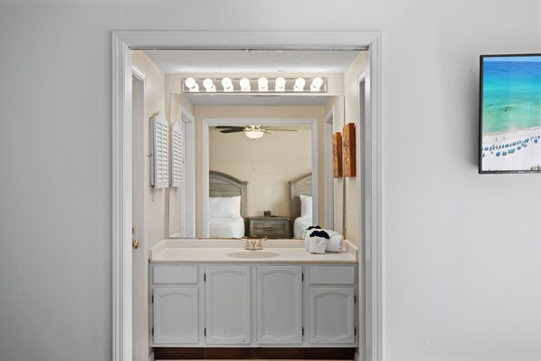 A bathroom with a vanity, a mirror, and a ceiling fan.