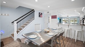 A modern kitchen with white cabinets, a stainless steel range hood, and a large window providing a view of the outdoors.