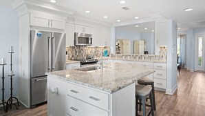 A modern kitchen with white cabinetry, stainless steel appliances, and a granite countertop island.