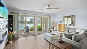 A spacious living room with a grey sofa, a wooden coffee table, and a ceiling fan.