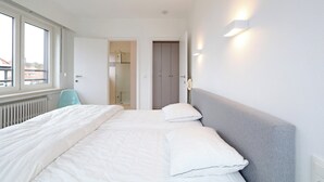 Hotelkamer met een groot bed, nachtkastje, stoel en uitzicht op de stad.