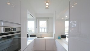 Een moderne keuken met witte kasten, een ingebouwde oven, een raam en een spoelbak.