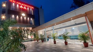 L’entrée d’un hôtel au design moderne, avec une façade en verre et des plantes en pot.