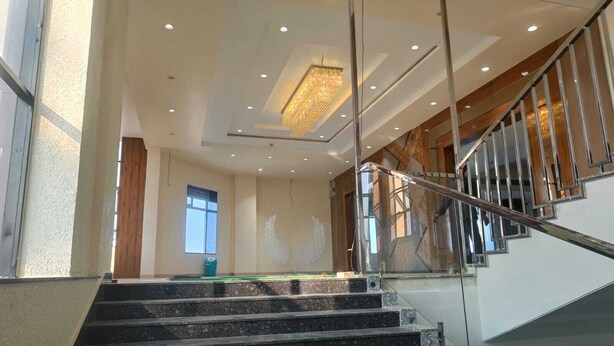 Un escalier doté d’une rampe en verre menant à un palier surmonté d’un lustre.