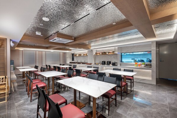 A modern dining area with marble tables and chairs, a kitchen in the background, and a unique ceiling design. - Dingshe Hotel (Guangzhou)