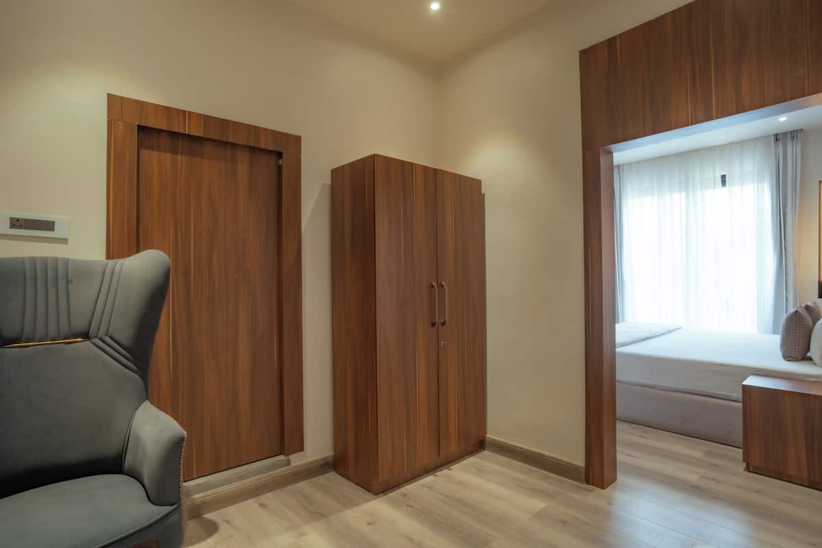 Une chambre à coucher avec un lit, un canapé gris, des armoires en bois et une fenêtre avec des rideaux.
