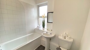 Een moderne badkamer met een bad, wastafel en toilet.