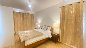 Een slaapkamer met een houten bed, twee bedlampen en een groot raam met gordijnen.